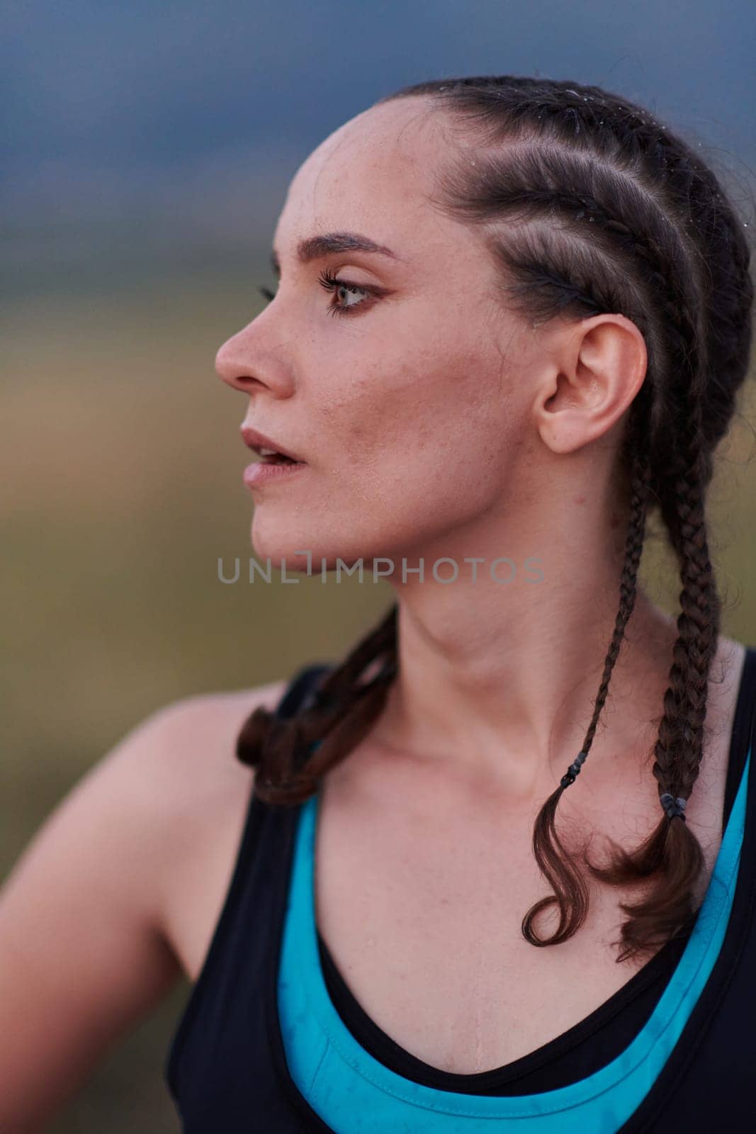 A close-up captures the raw dedication of a female athlete as she rests, sweat glistening, after a rigorous running session, embodying the true spirit of perseverance and commitment to her fitness journey