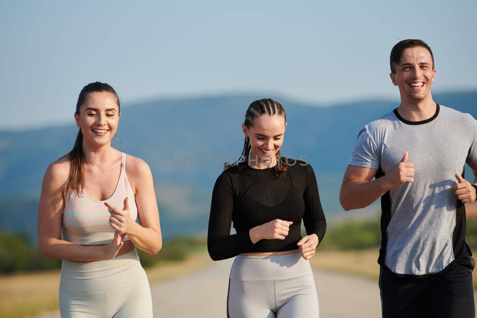 A group of friends maintains a healthy lifestyle by running outdoors on a sunny day, bonding over fitness and enjoying the energizing effects of exercise and nature by dotshock