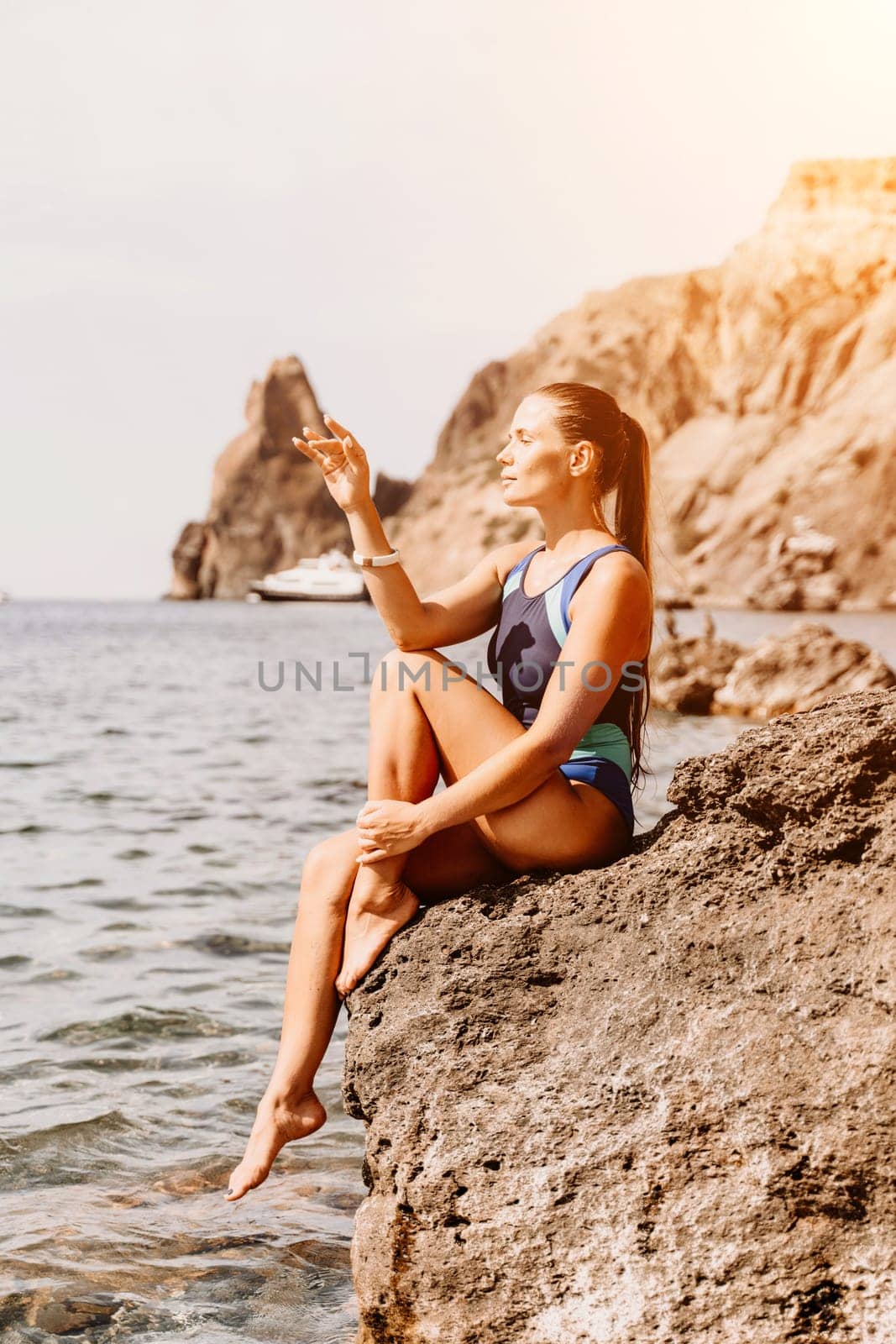 Woman travel summer sea. A happy tourist in a blue bikini enjoying the scenic view of the sea and volcanic mountains while taking pictures to capture the memories of her travel adventure