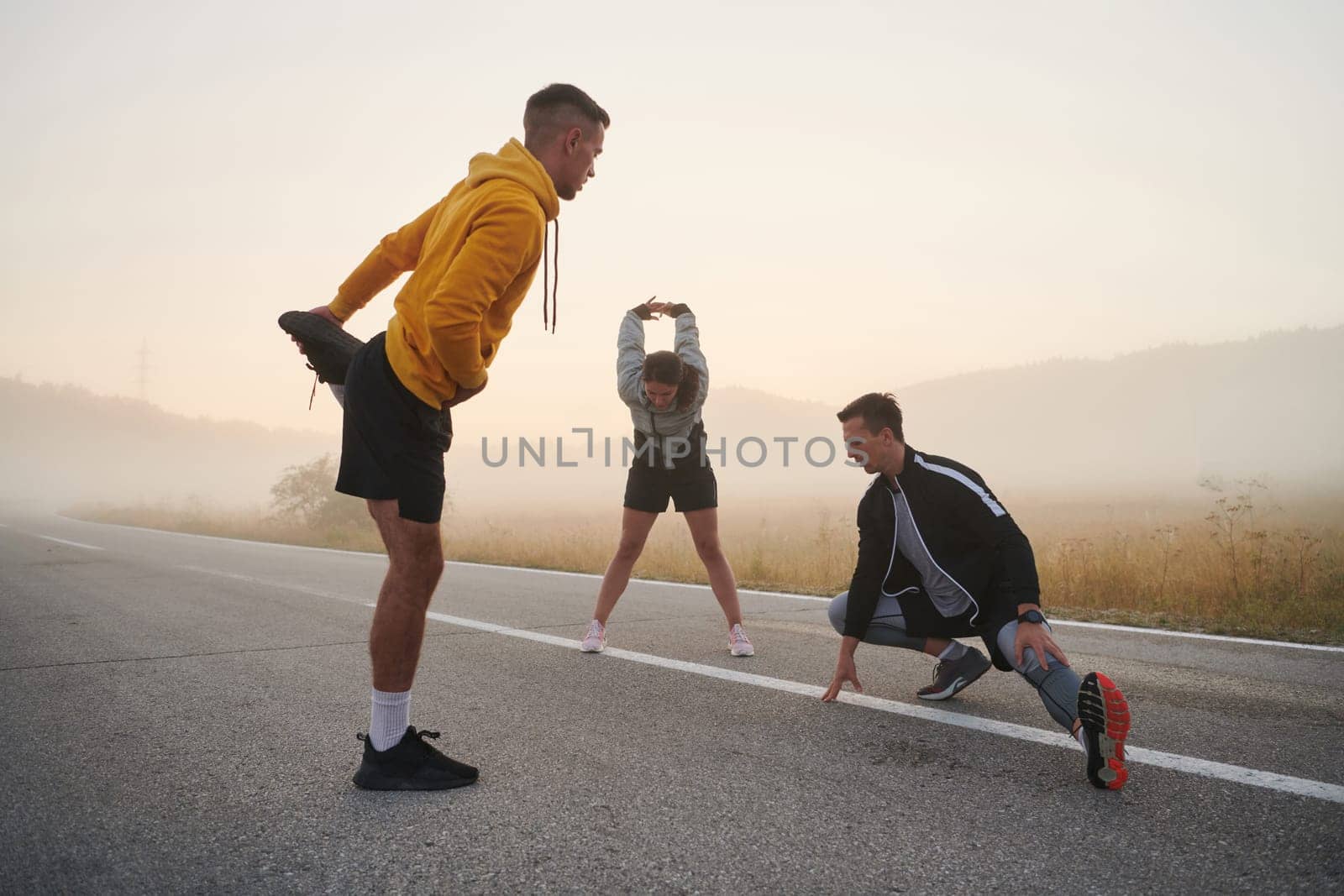 Diverse Athletes Prepare: Dynamic Group Warms Up for Morning Run. by dotshock
