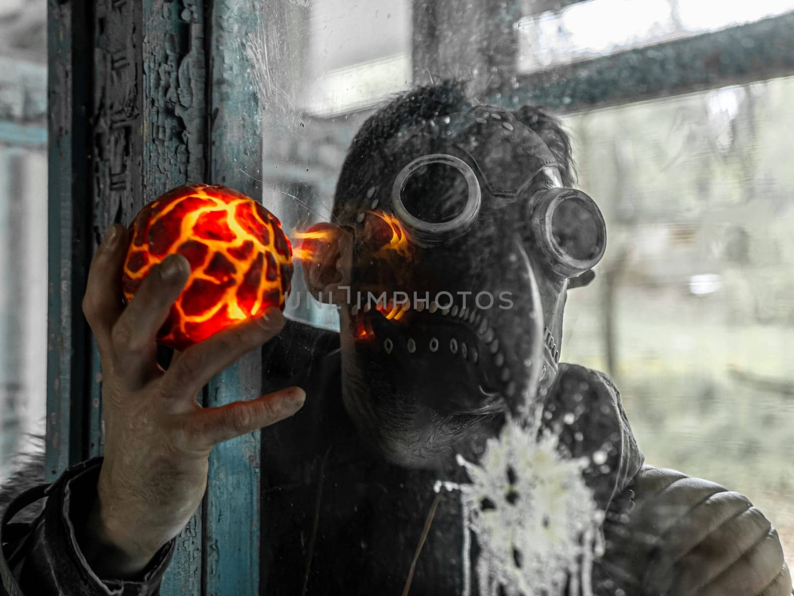 Cosplay of a stalker in a plague doctor mask holding a mysterious artifact and looking at it through glass