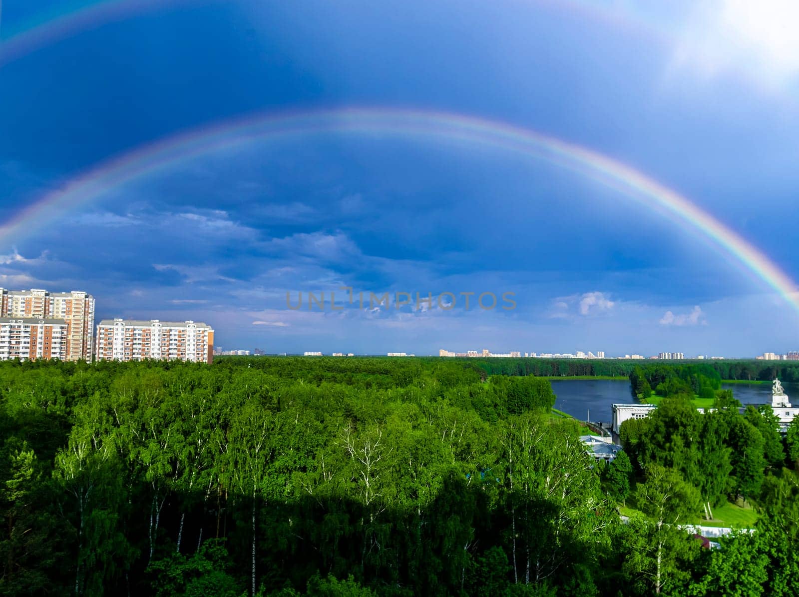 Rainbow over forest and calm lake water in Moscow