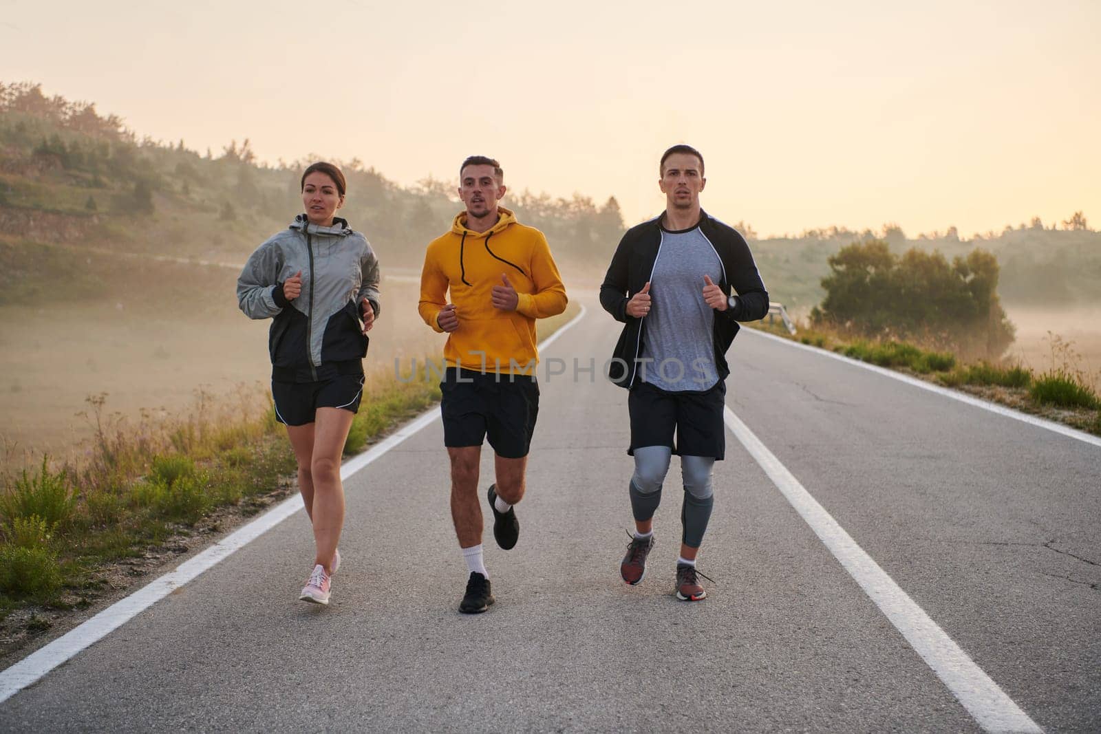 A group of sports colleagues huddle together for a pre-dawn run, the foggy air and early morning light creating an atmosphere of camaraderie and determination.