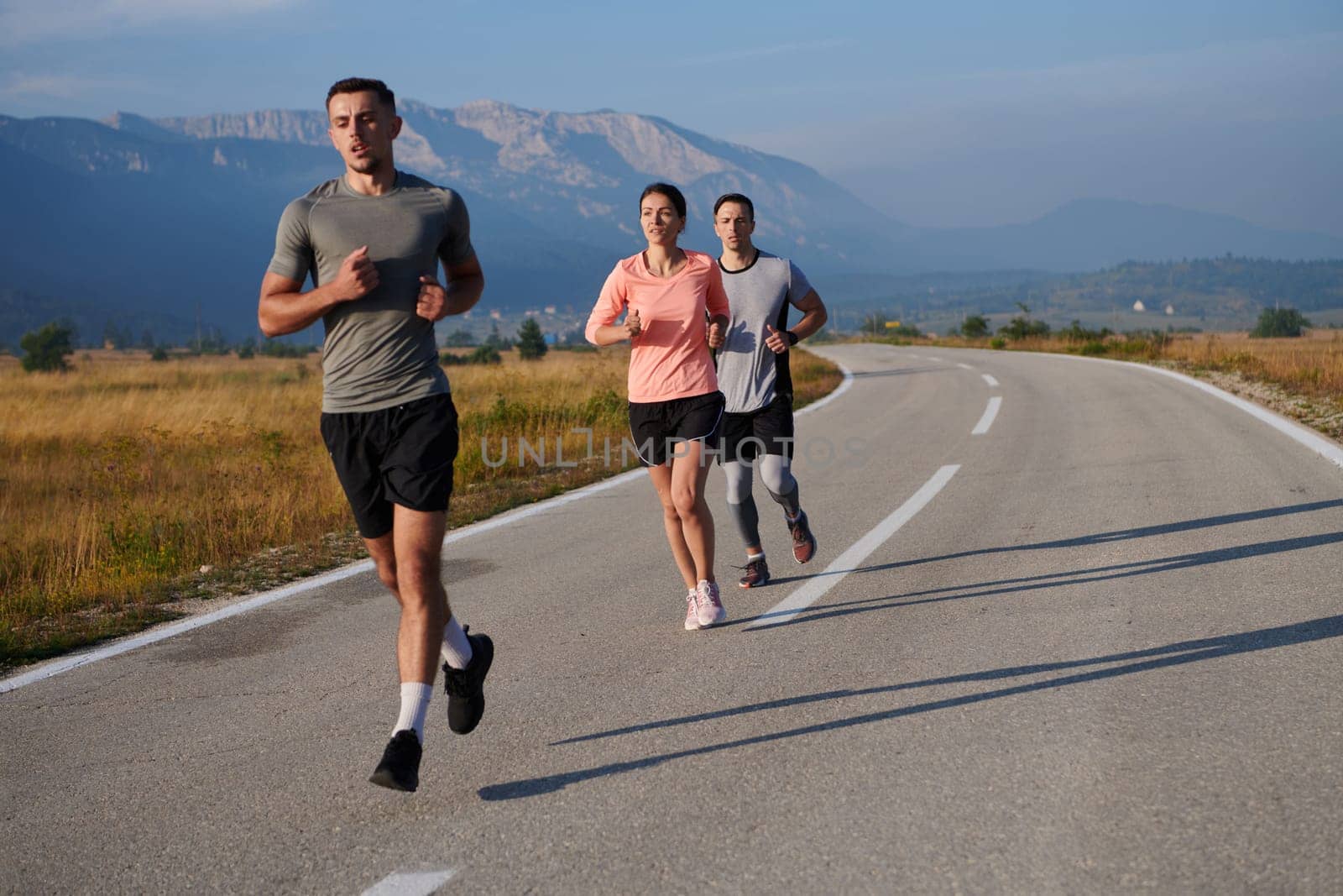 A group of friends maintains a healthy lifestyle by running outdoors on a sunny day, bonding over fitness and enjoying the energizing effects of exercise and nature by dotshock