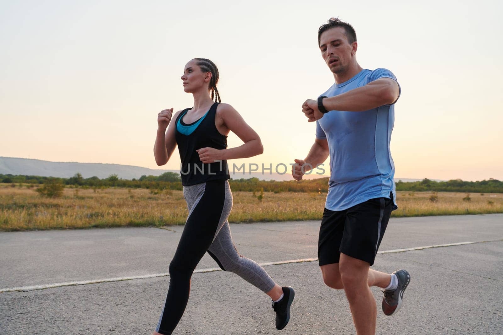 A vibrant couple dashes running the outdoors, embodying the essence of athleticism and romance, their confident strides reflecting a shared commitment to fitness and preparation for future marathon challenges.