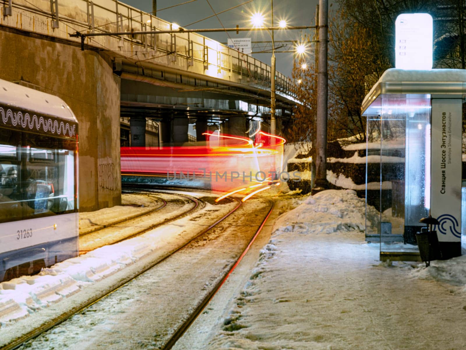 the tram leaves the stop in night city, motion blur view by lempro