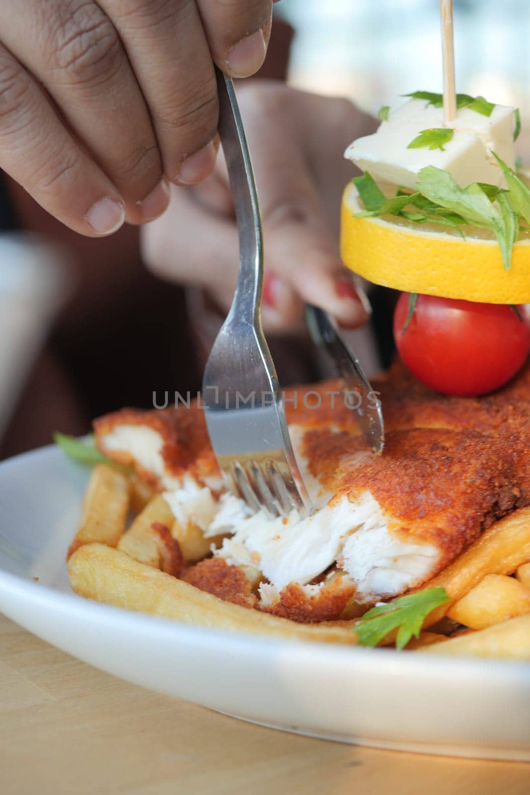 women eating Chicken schnitzel served with potato chips .