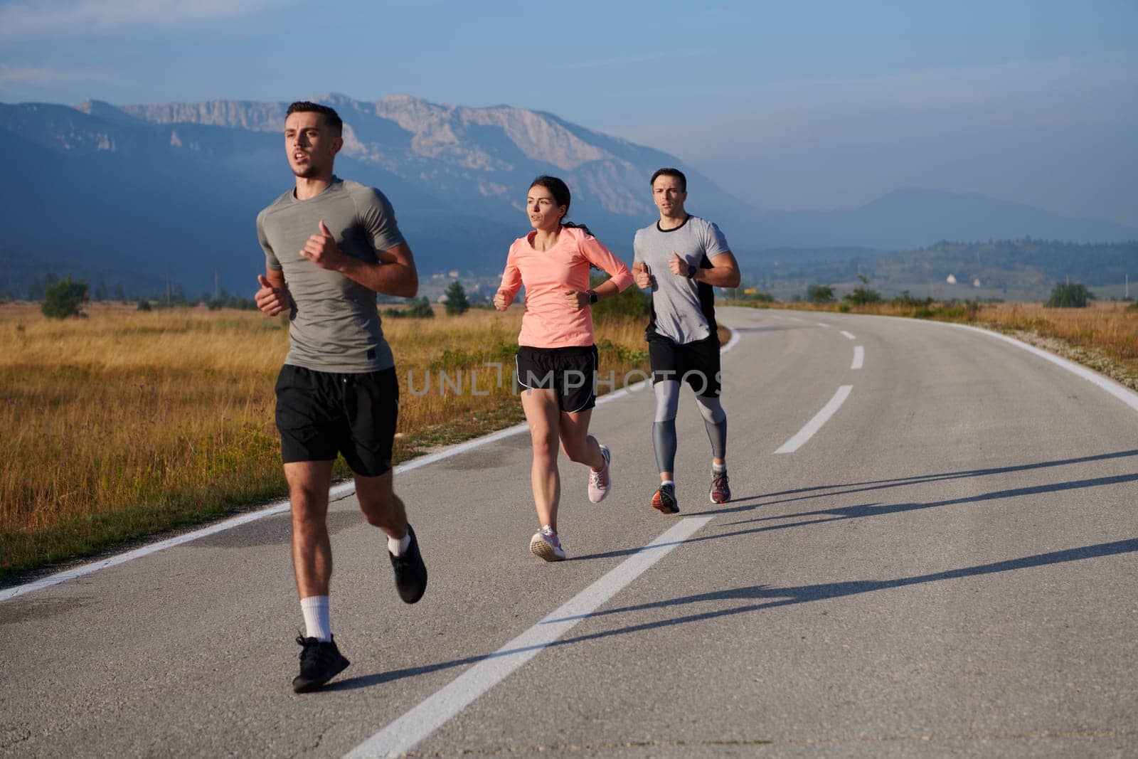 A group of friends maintains a healthy lifestyle by running outdoors on a sunny day, bonding over fitness and enjoying the energizing effects of exercise and nature by dotshock