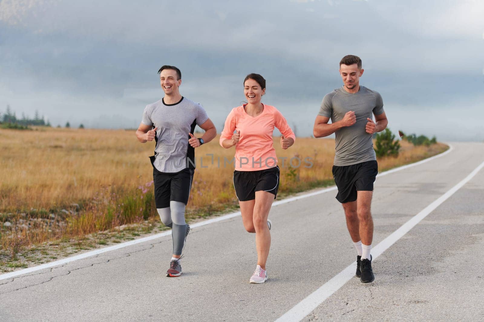 A group of friends, athletes, and joggers embrace the early morning hours as they run through the misty dawn, energized by the rising sun and surrounded by the tranquil beauty of nature.