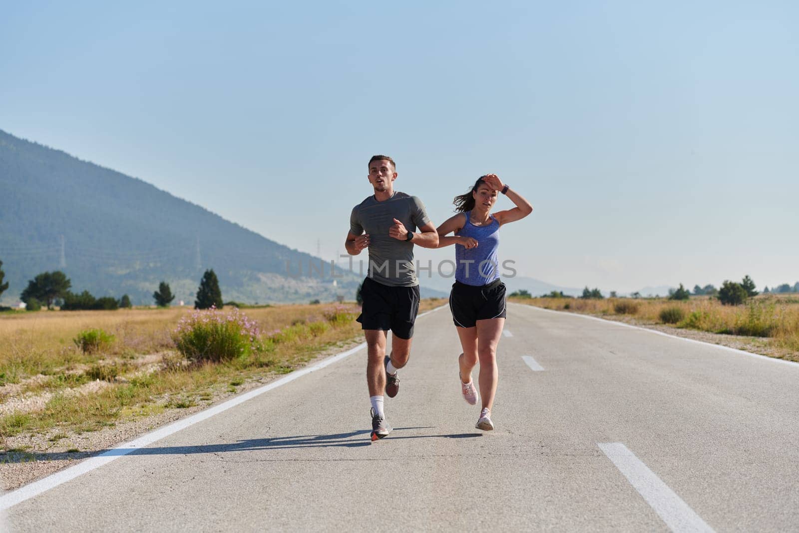 A couple runs through a sun-dappled road, their bodies strong and healthy, their love for each other and the outdoors evident in every stride.