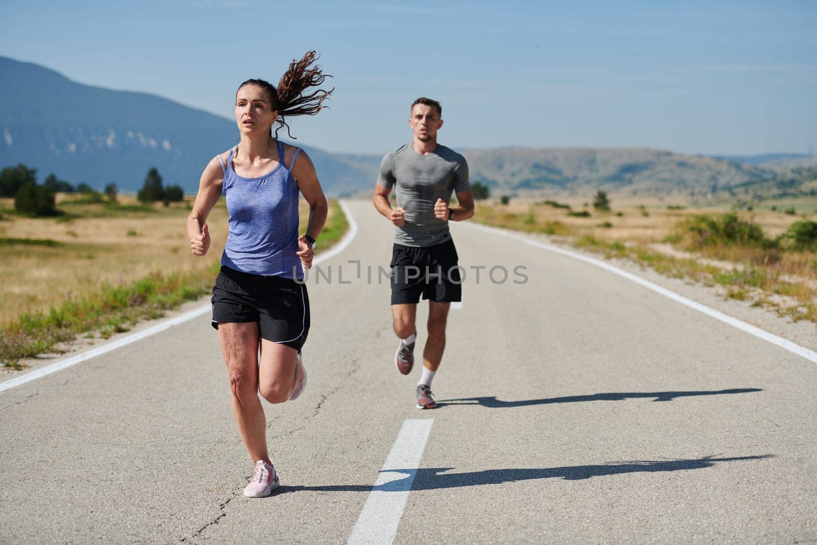 A couple runs through a sun-dappled road, their bodies strong and healthy, their love for each other and the outdoors evident in every stride.