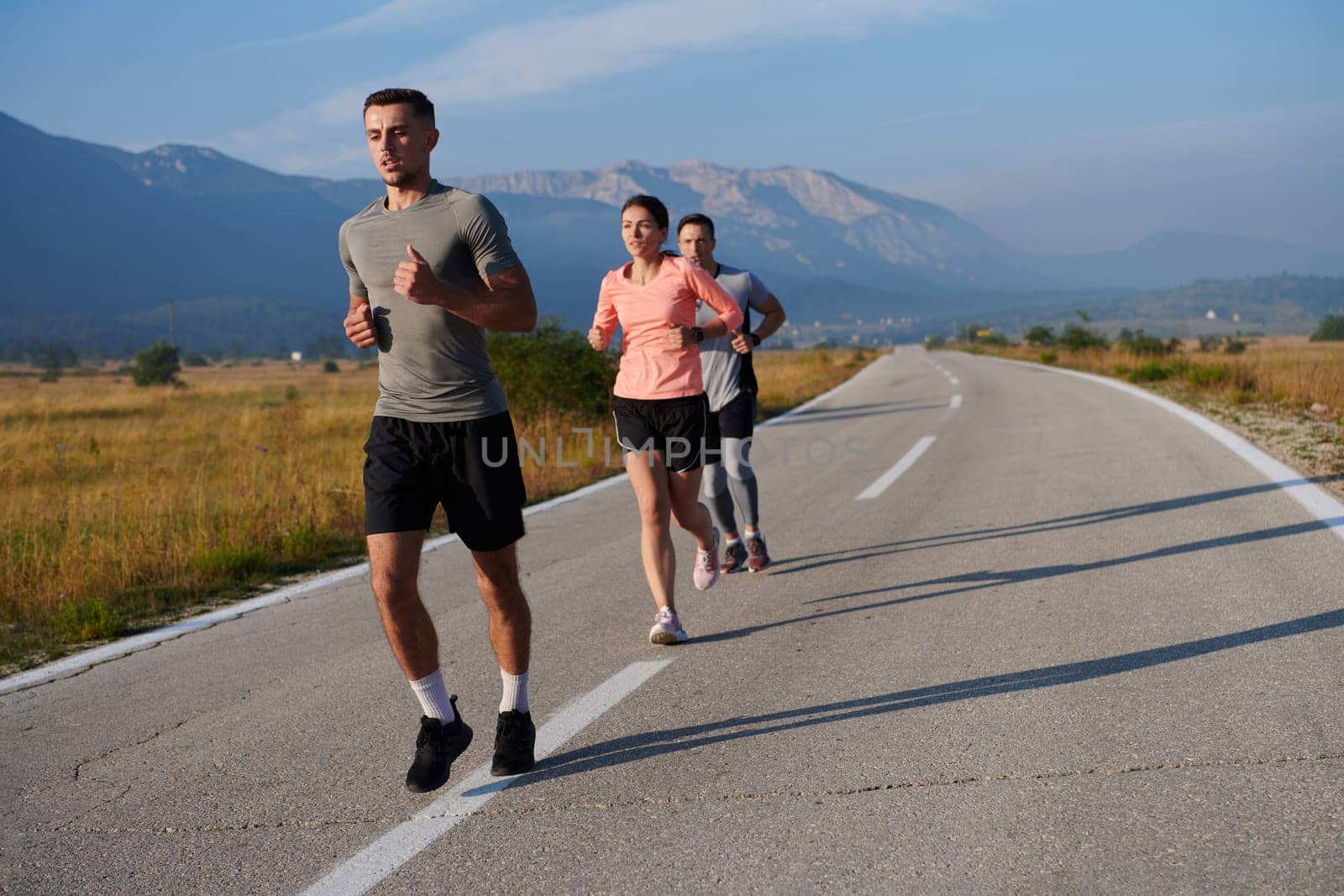 A group of friends maintains a healthy lifestyle by running outdoors on a sunny day, bonding over fitness and enjoying the energizing effects of exercise and nature by dotshock