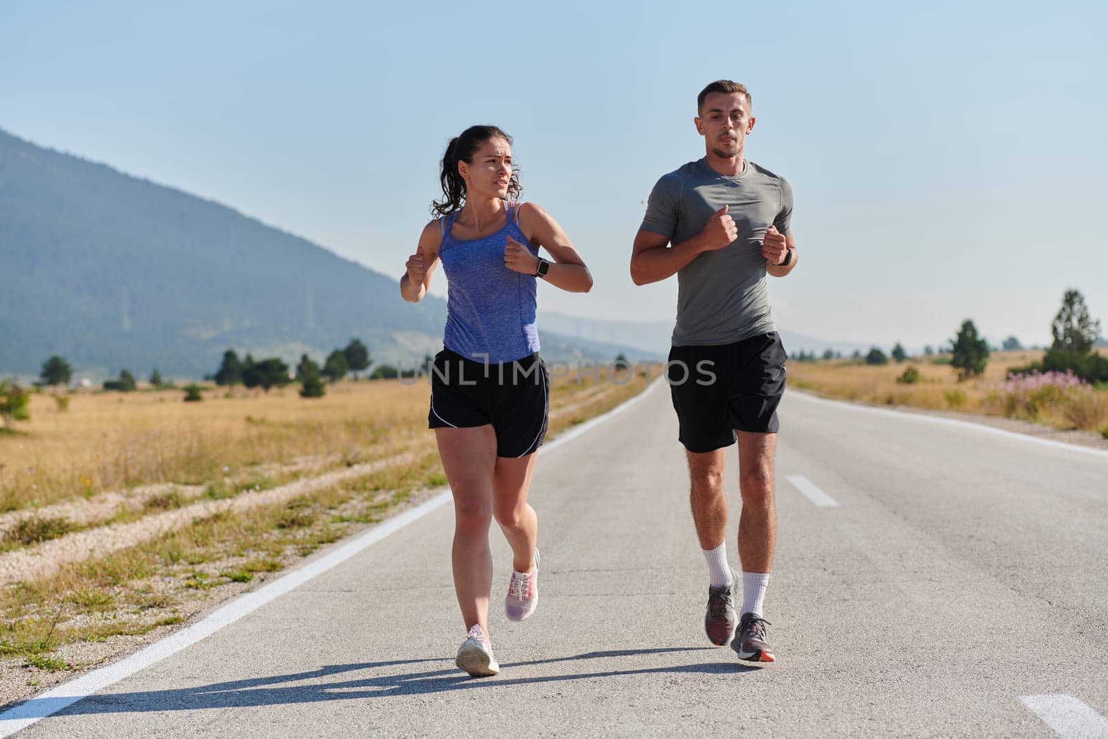 A couple runs through a sun-dappled road, their bodies strong and healthy, their love for each other and the outdoors evident in every stride.