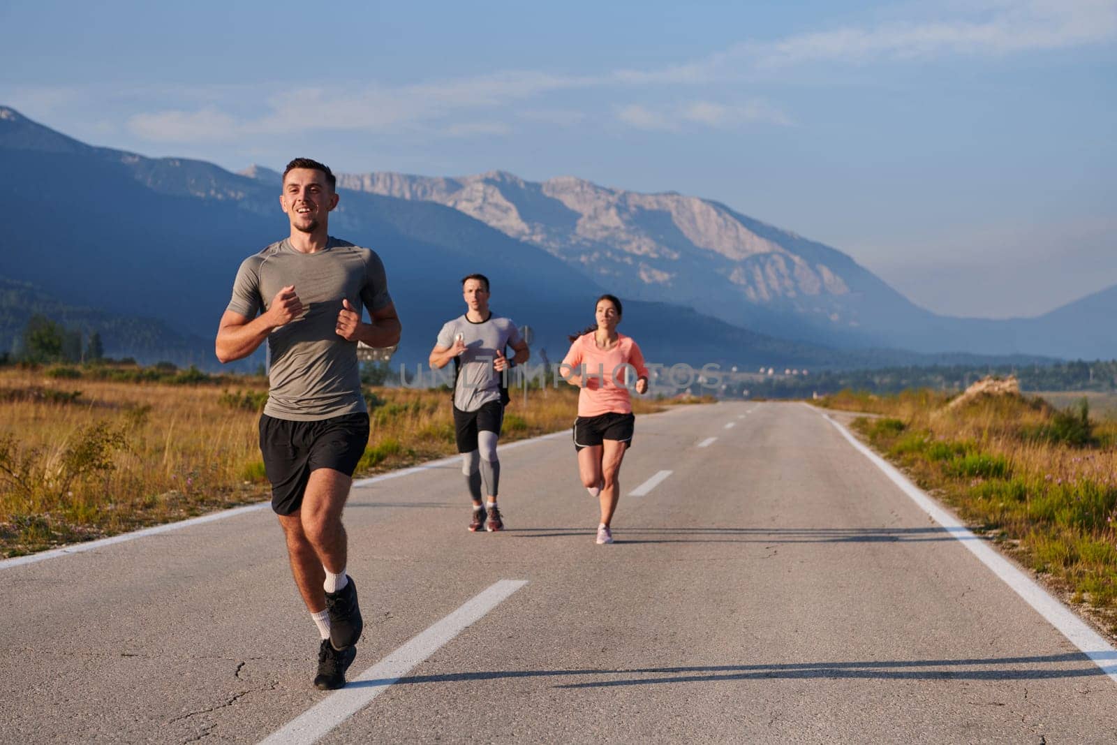 A group of friends maintains a healthy lifestyle by running outdoors on a sunny day, bonding over fitness and enjoying the energizing effects of exercise and nature by dotshock