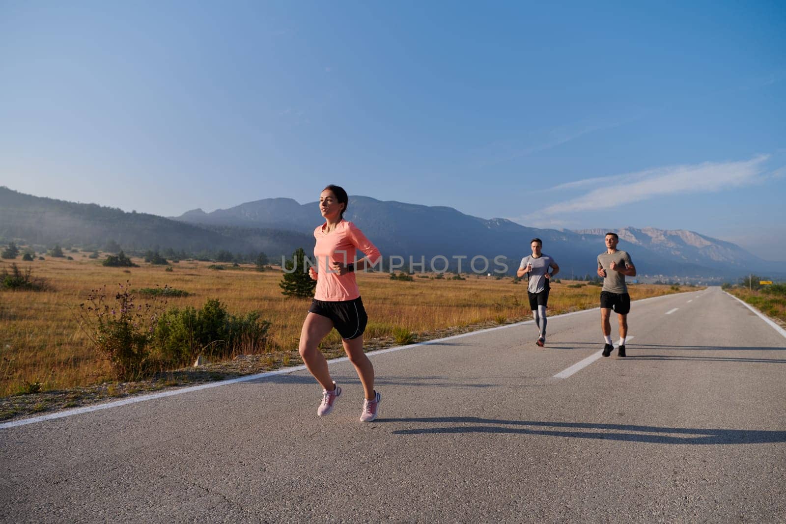 A group of friends maintains a healthy lifestyle by running outdoors on a sunny day, bonding over fitness and enjoying the energizing effects of exercise and nature.