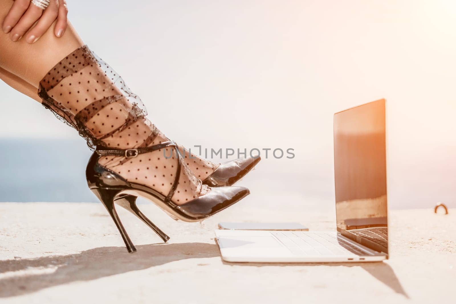 Woman sea laptop. Business woman in yellow hat freelancer with laptop working over blue sea beach. Girl relieves stress from work. Freelance, digital nomad, travel and holidays concept by panophotograph