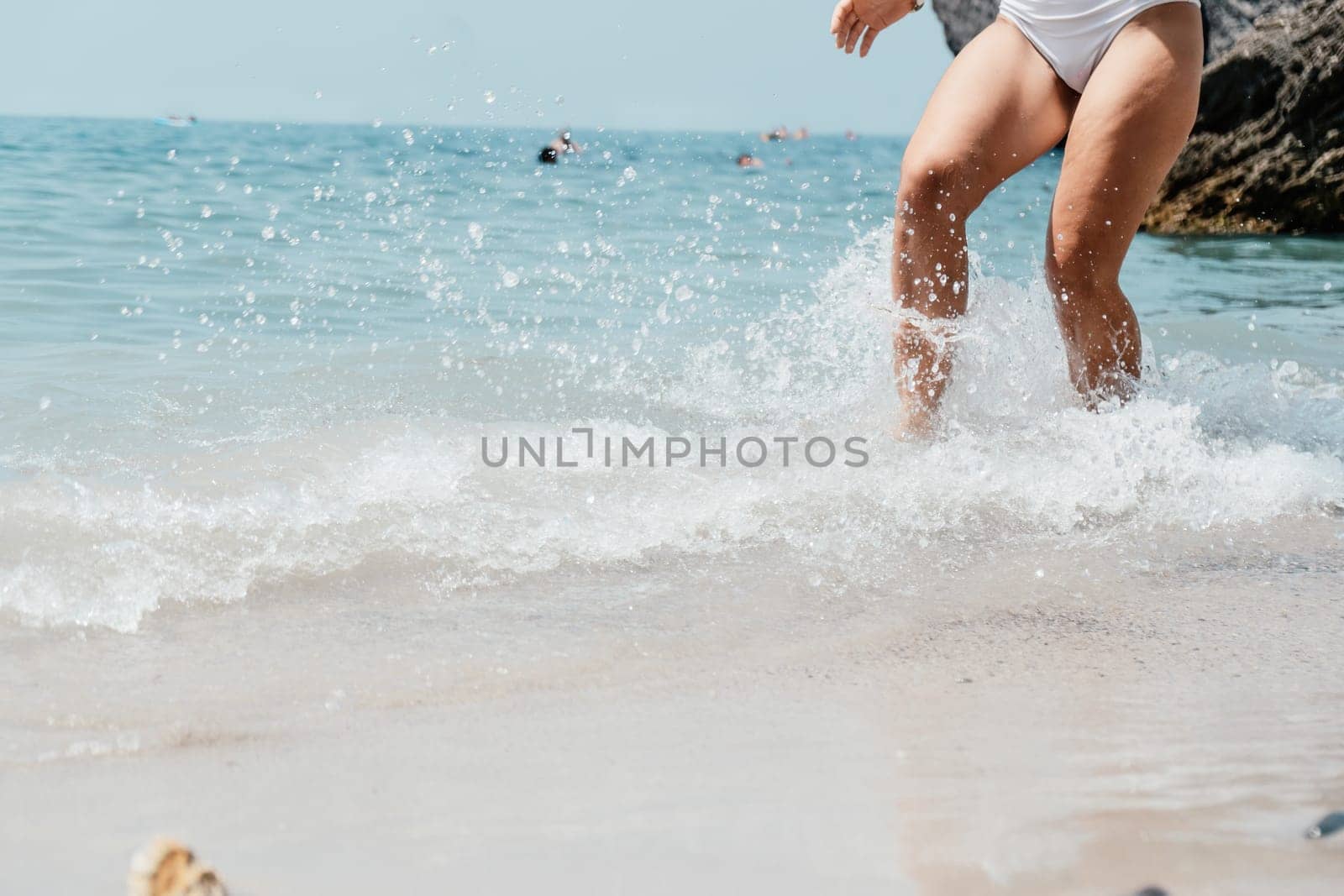Sea beach travel - woman walking on sand beach leaving footprints in the white sand. Female legs walking along the seaside barefoot, close-up of the tanned legs of a girl coming out of the water