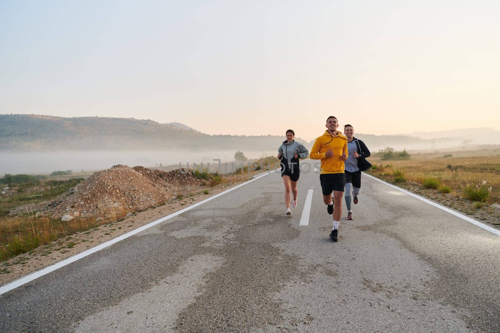 A group of friends, athletes, and joggers embrace the early morning hours as they run through the misty dawn, energized by the rising sun and surrounded by the tranquil beauty of nature by dotshock