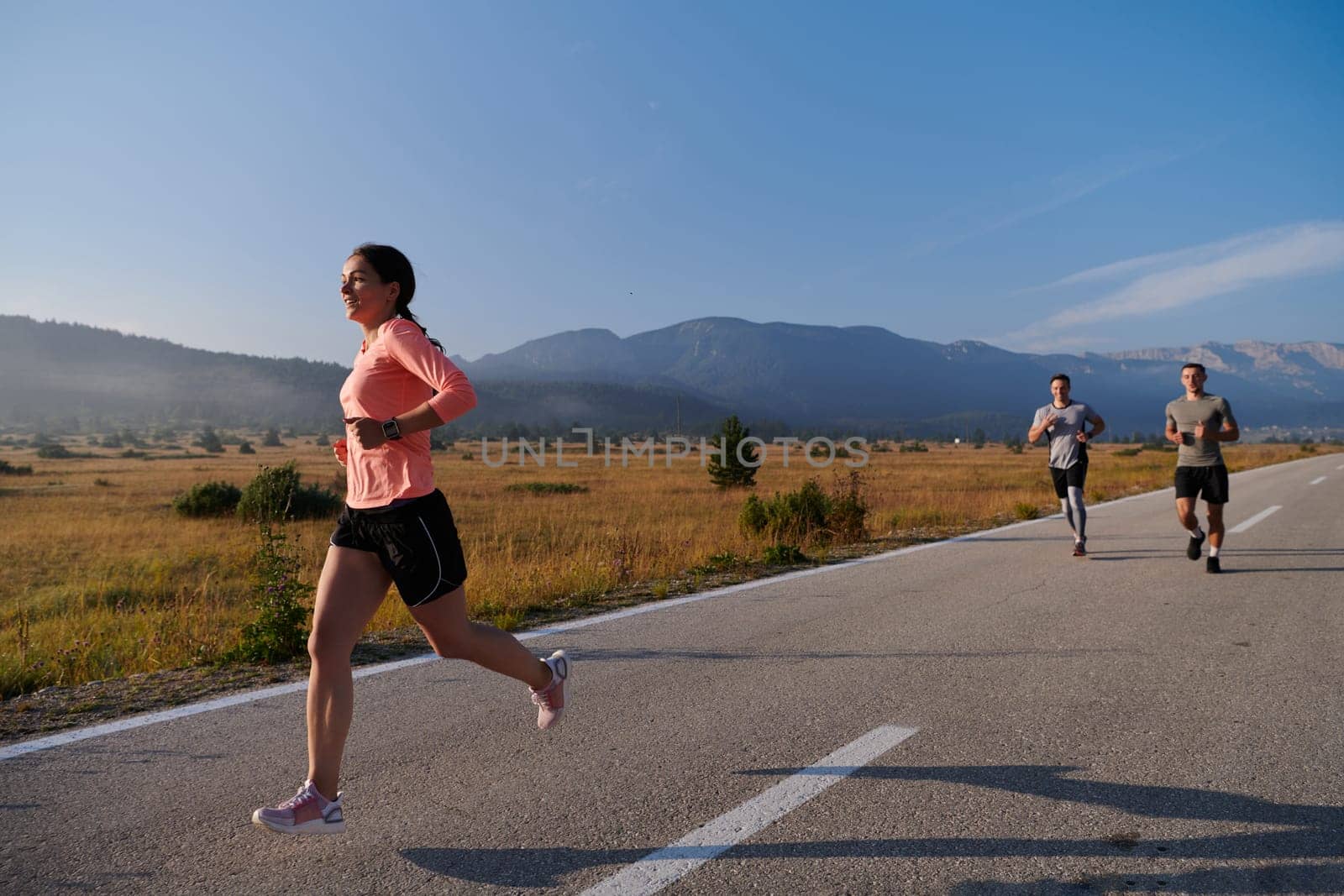 A group of friends maintains a healthy lifestyle by running outdoors on a sunny day, bonding over fitness and enjoying the energizing effects of exercise and nature.