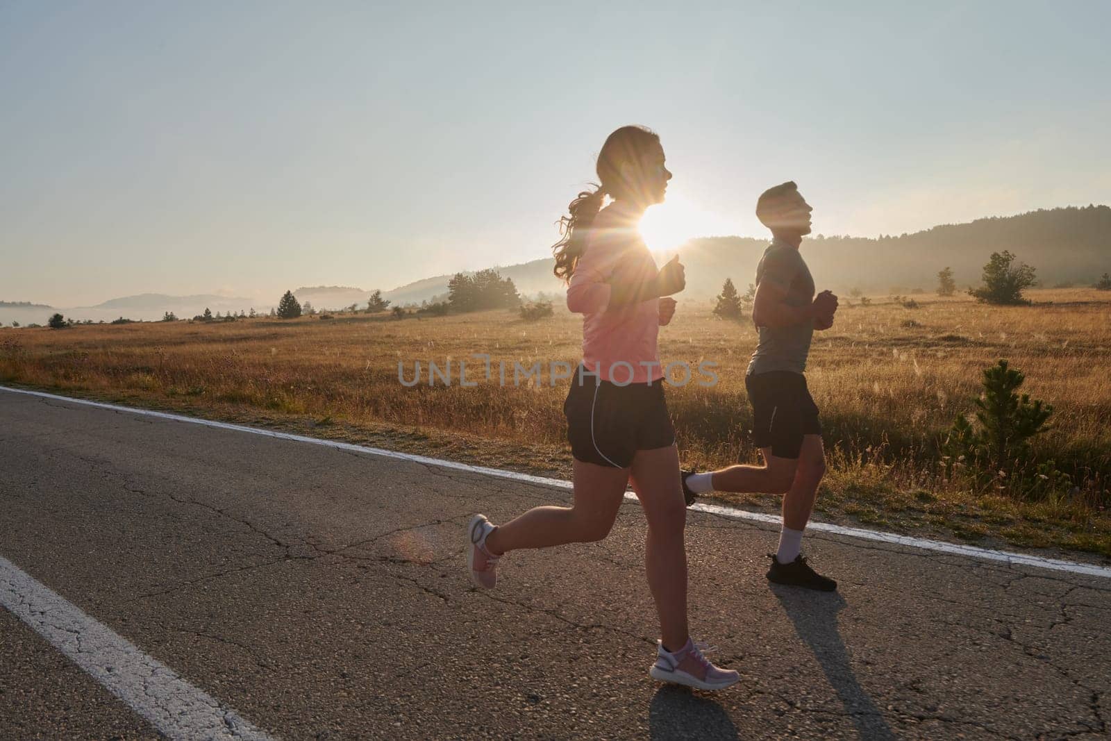 A couple runs through a sun-dappled road, their bodies strong and healthy, their love for each other and the outdoors evident in every stride.