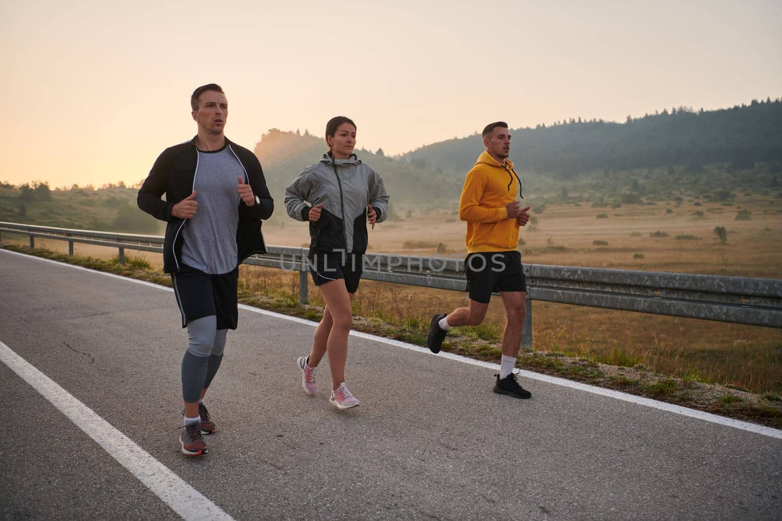 A group of sports colleagues huddle together for a pre-dawn run, the foggy air and early morning light creating an atmosphere of camaraderie and determination.