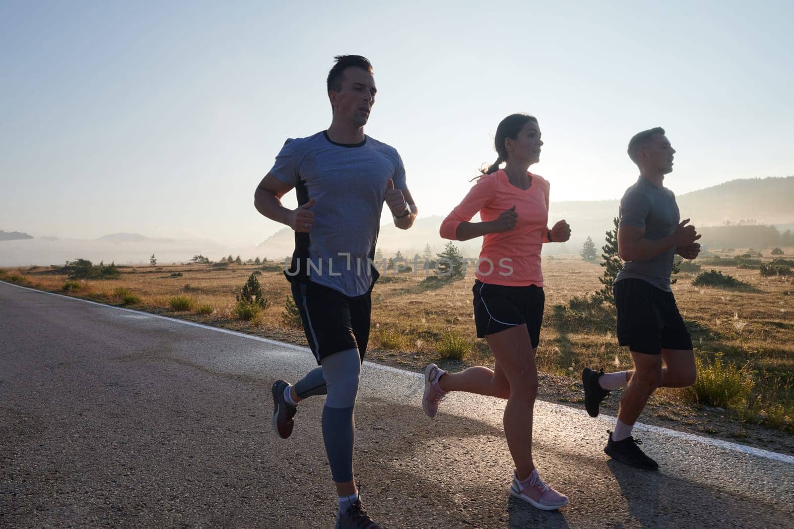 A group of friends, athletes, and joggers embrace the early morning hours as they run through the misty dawn, energized by the rising sun and surrounded by the tranquil beauty of nature by dotshock