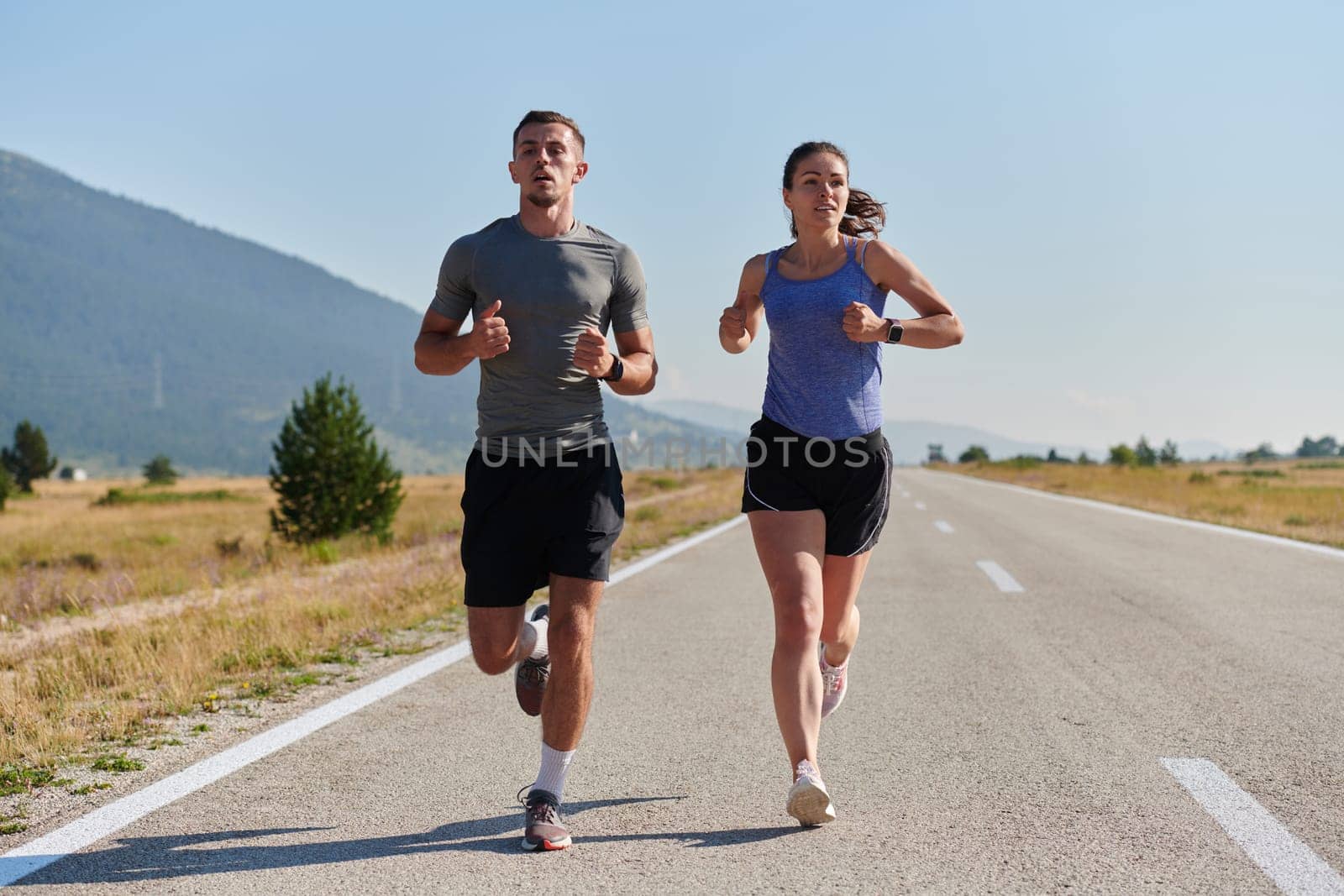 A couple runs through a sun-dappled road, their bodies strong and healthy, their love for each other and the outdoors evident in every stride.