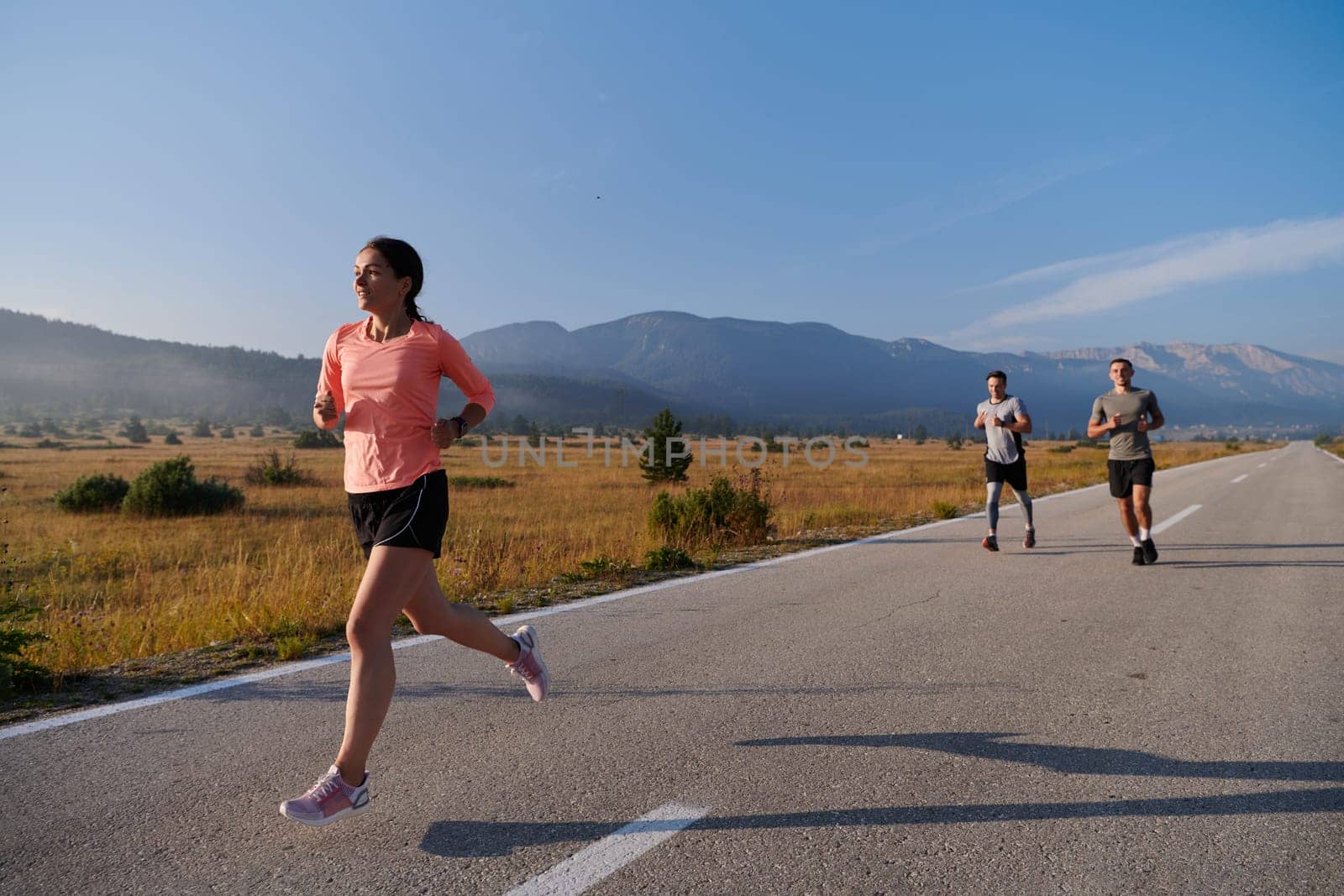 A group of friends maintains a healthy lifestyle by running outdoors on a sunny day, bonding over fitness and enjoying the energizing effects of exercise and nature by dotshock