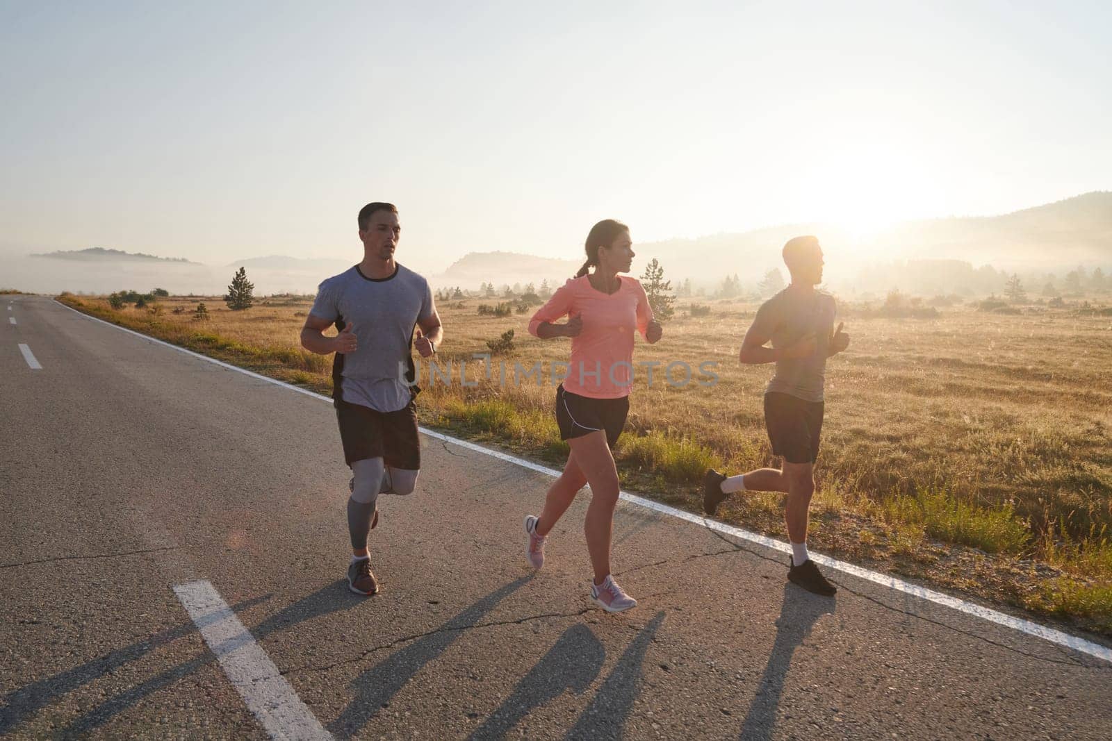 A group of friends, athletes, and joggers embrace the early morning hours as they run through the misty dawn, energized by the rising sun and surrounded by the tranquil beauty of nature by dotshock