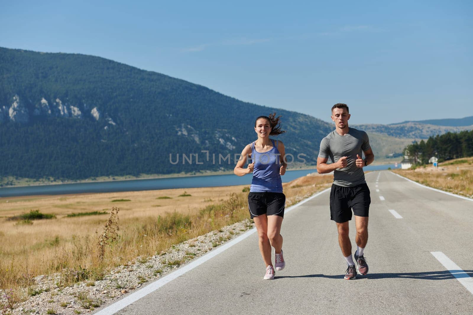 A couple runs through a sun-dappled road, their bodies strong and healthy, their love for each other and the outdoors evident in every stride.