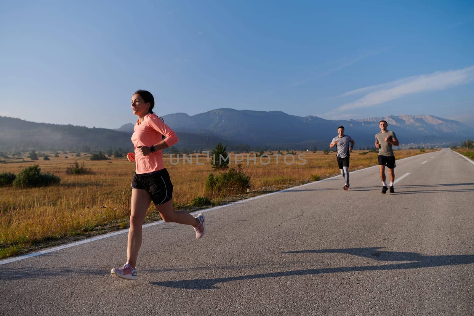 A group of friends maintains a healthy lifestyle by running outdoors on a sunny day, bonding over fitness and enjoying the energizing effects of exercise and nature by dotshock