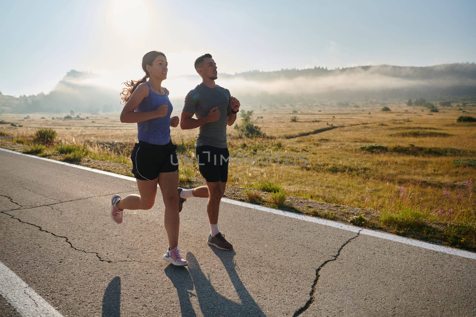 A couple runs through a sun-dappled road, their bodies strong and healthy, their love for each other and the outdoors evident in every stride.