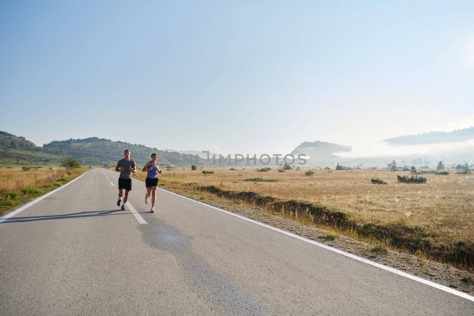 A couple runs through a sun-dappled road, their bodies strong and healthy, their love for each other and the outdoors evident in every stride.