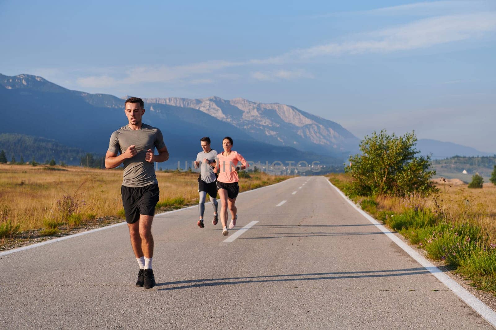 A group of friends maintains a healthy lifestyle by running outdoors on a sunny day, bonding over fitness and enjoying the energizing effects of exercise and nature by dotshock