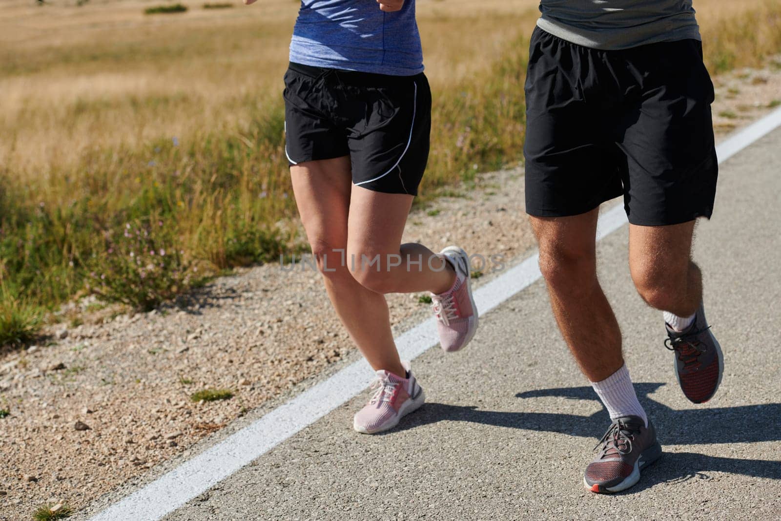 A couple runs through a sun-dappled road, their bodies strong and healthy, their love for each other and the outdoors evident in every stride.