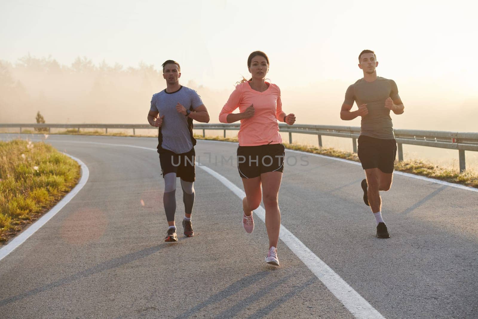 A group of friends, athletes, and joggers embrace the early morning hours as they run through the misty dawn, energized by the rising sun and surrounded by the tranquil beauty of nature by dotshock