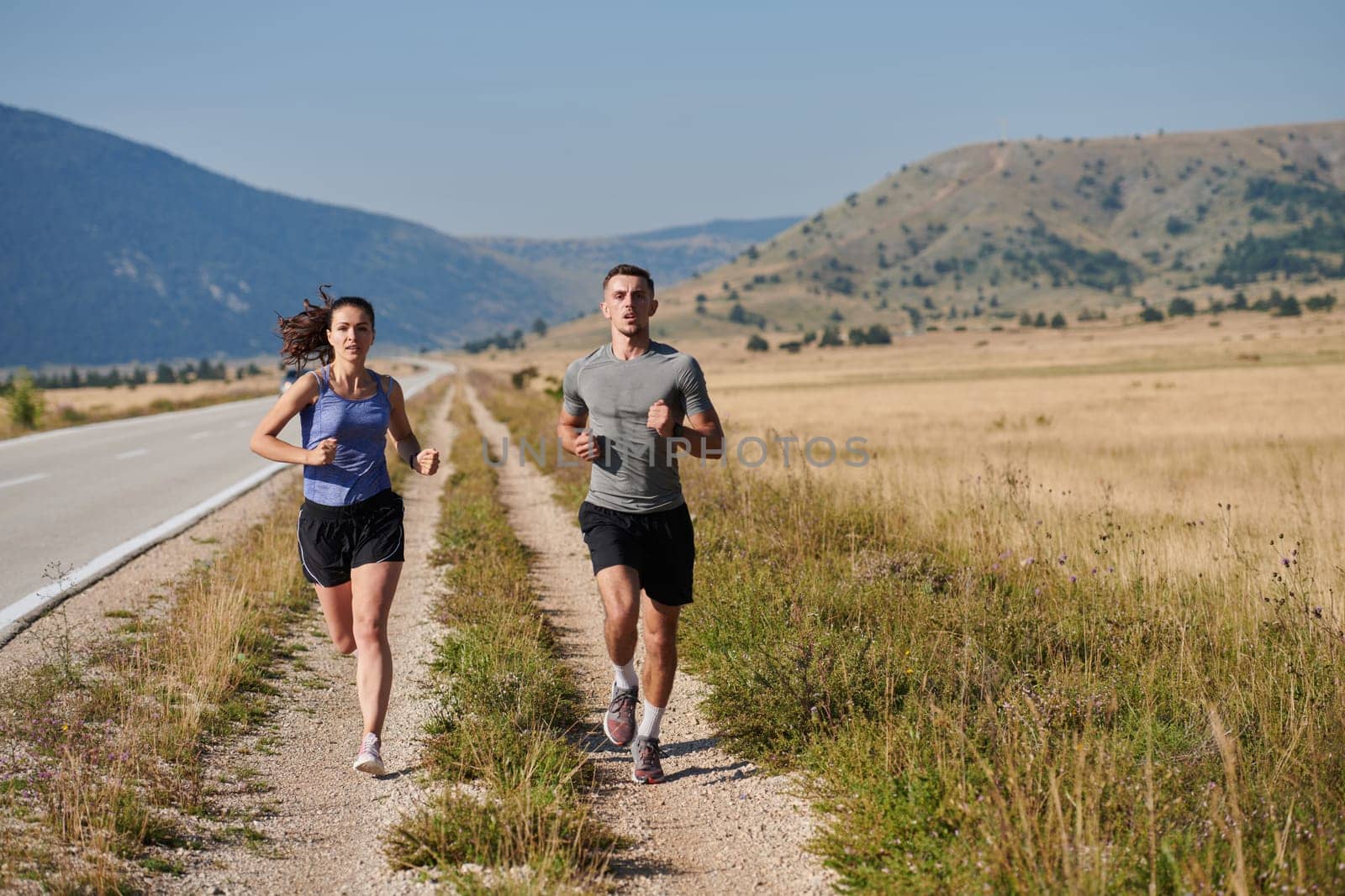 A couple runs through a sun-dappled road, their bodies strong and healthy, their love for each other and the outdoors evident in every stride.