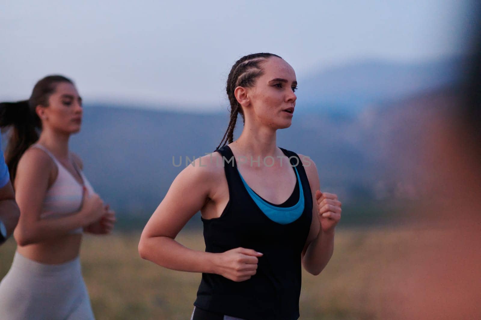 A diverse group of runners finds motivation and inspiration in each other as they train together for an upcoming competition, set against a breathtaking sunset backdrop.