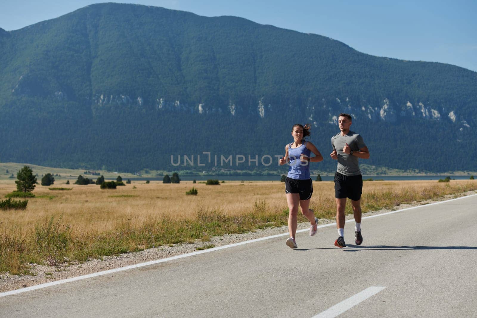 A couple runs through a sun-dappled road, their bodies strong and healthy, their love for each other and the outdoors evident in every stride.