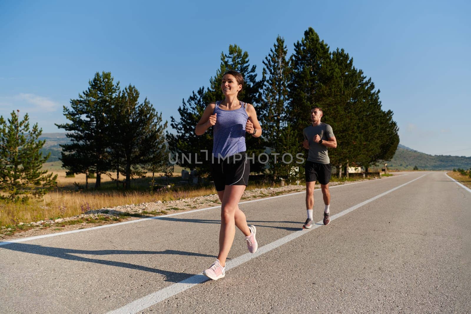 A couple runs through a sun-dappled road, their bodies strong and healthy, their love for each other and the outdoors evident in every stride.