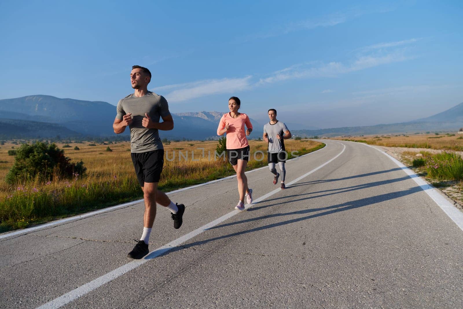 A group of friends maintains a healthy lifestyle by running outdoors on a sunny day, bonding over fitness and enjoying the energizing effects of exercise and nature by dotshock