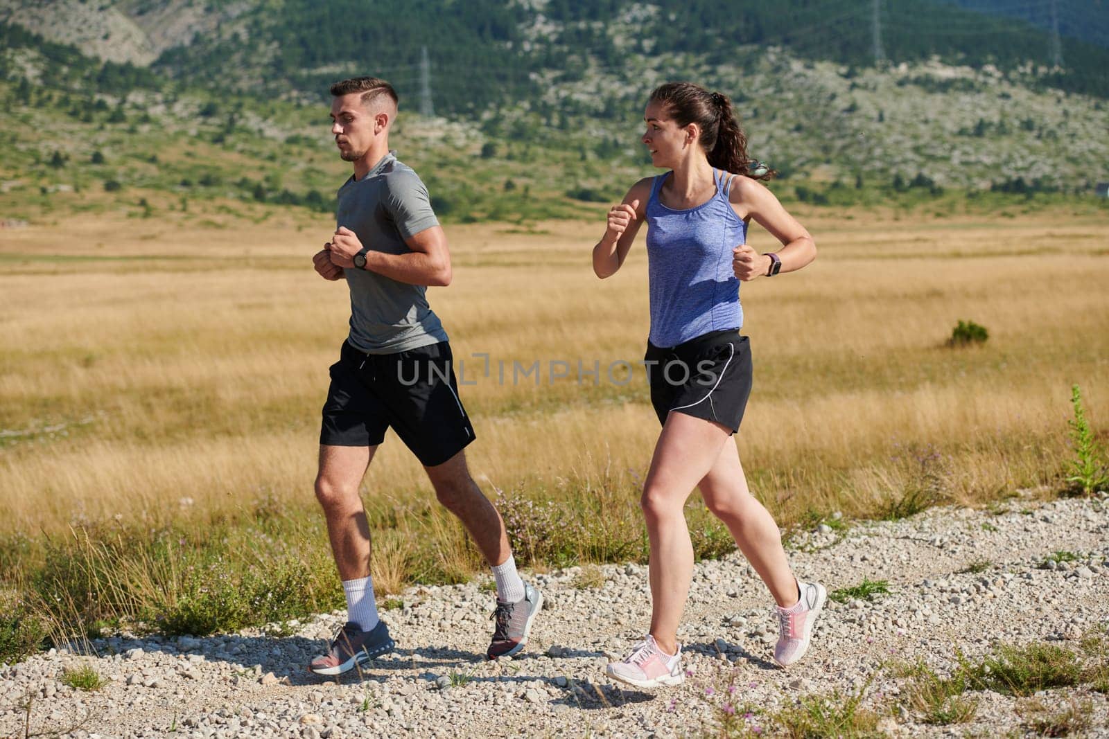 A couple runs through a sun-dappled road, their bodies strong and healthy, their love for each other and the outdoors evident in every stride.