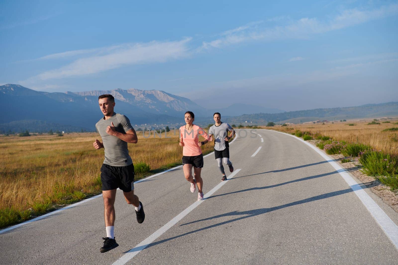 A group of friends maintains a healthy lifestyle by running outdoors on a sunny day, bonding over fitness and enjoying the energizing effects of exercise and nature by dotshock