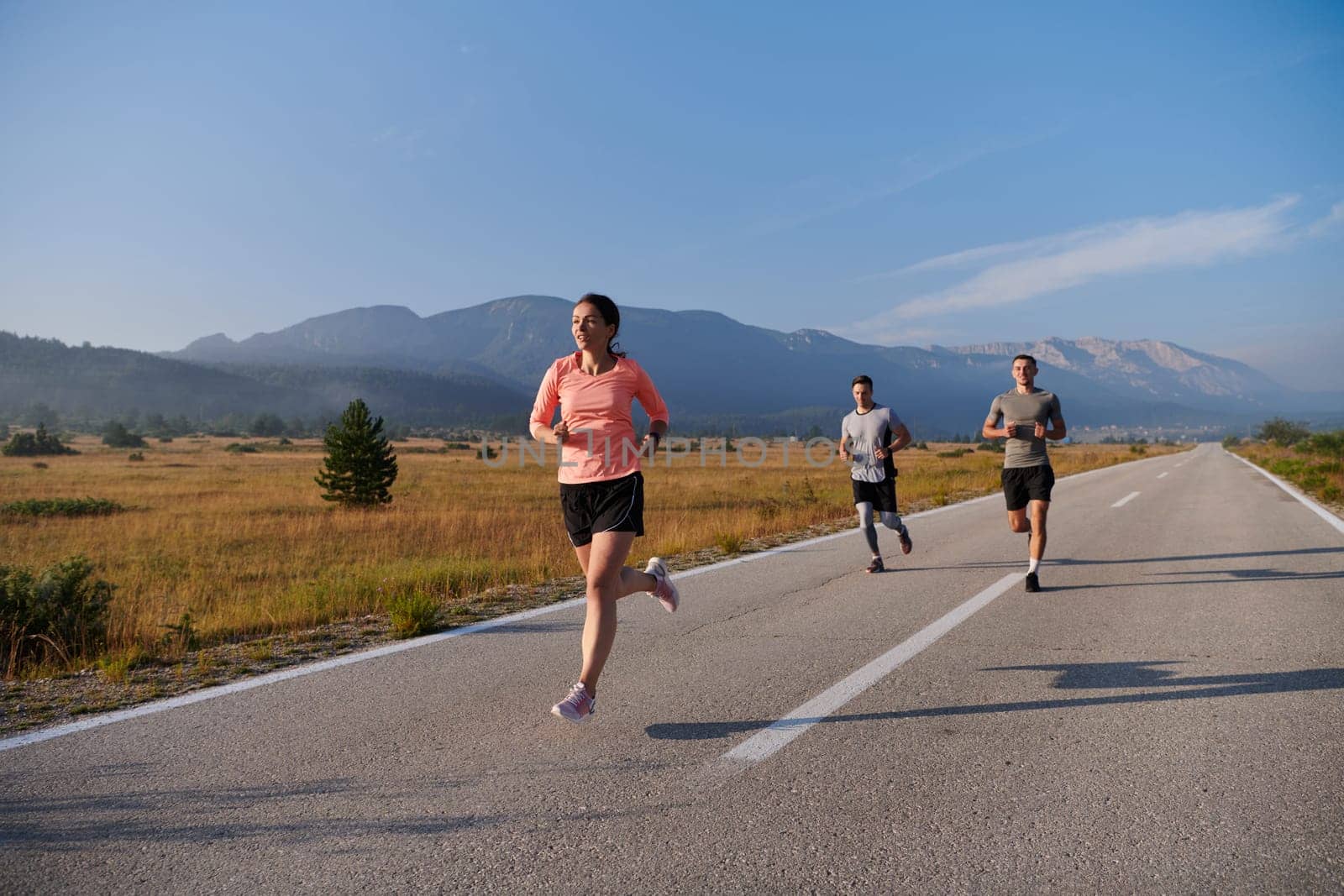 A group of friends maintains a healthy lifestyle by running outdoors on a sunny day, bonding over fitness and enjoying the energizing effects of exercise and nature.