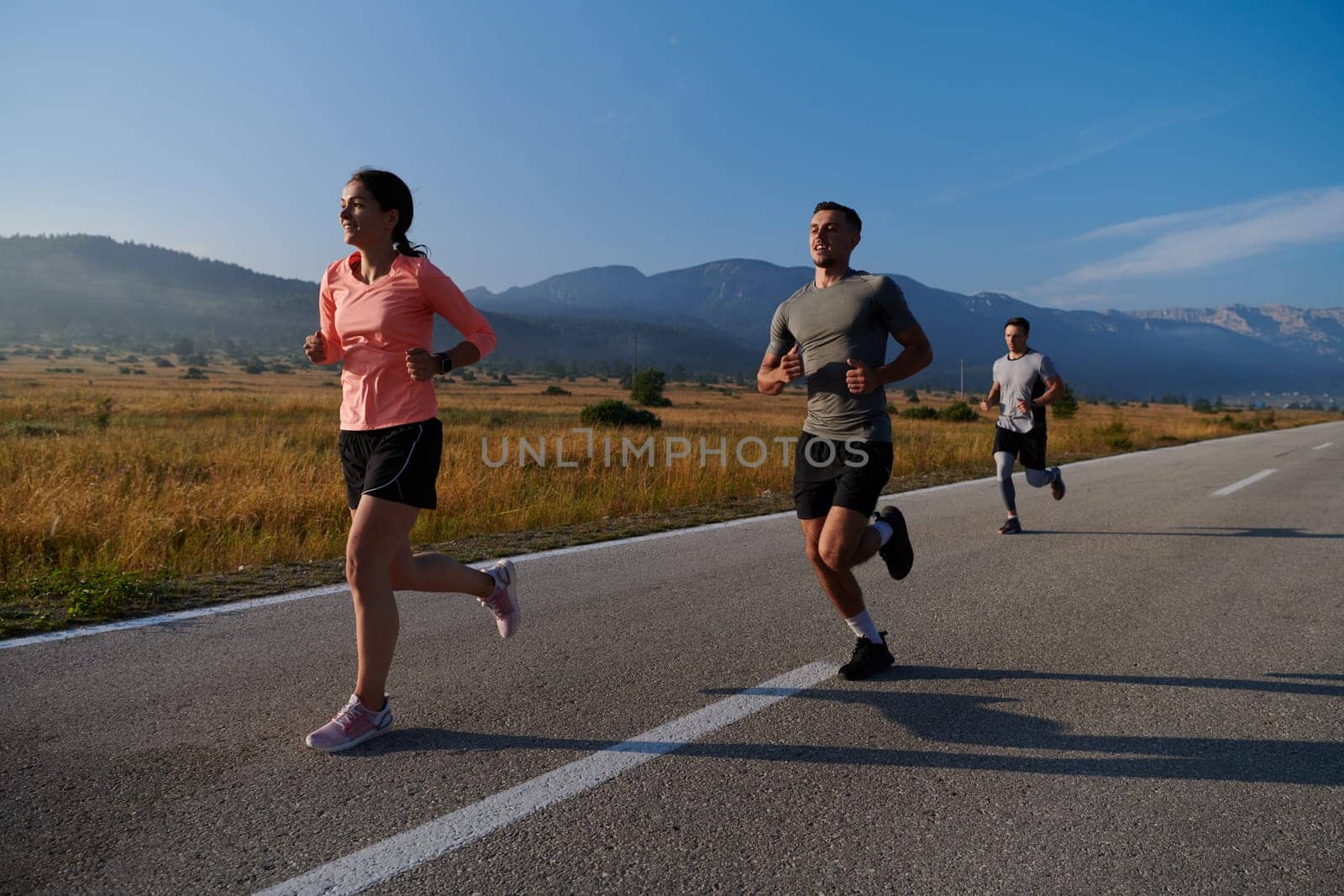 A group of friends maintains a healthy lifestyle by running outdoors on a sunny day, bonding over fitness and enjoying the energizing effects of exercise and nature by dotshock