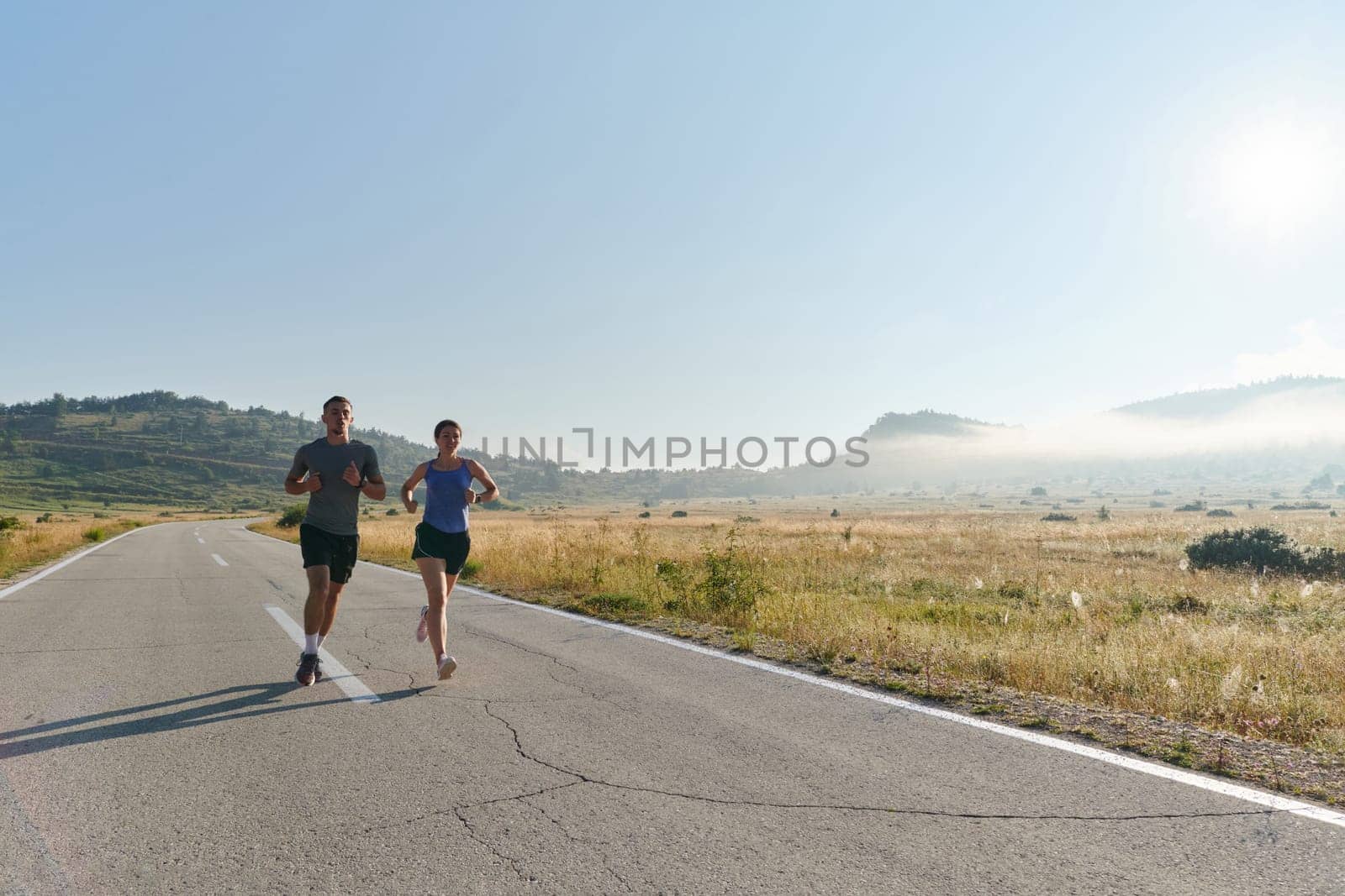 A couple runs through a sun-dappled road, their bodies strong and healthy, their love for each other and the outdoors evident in every stride.