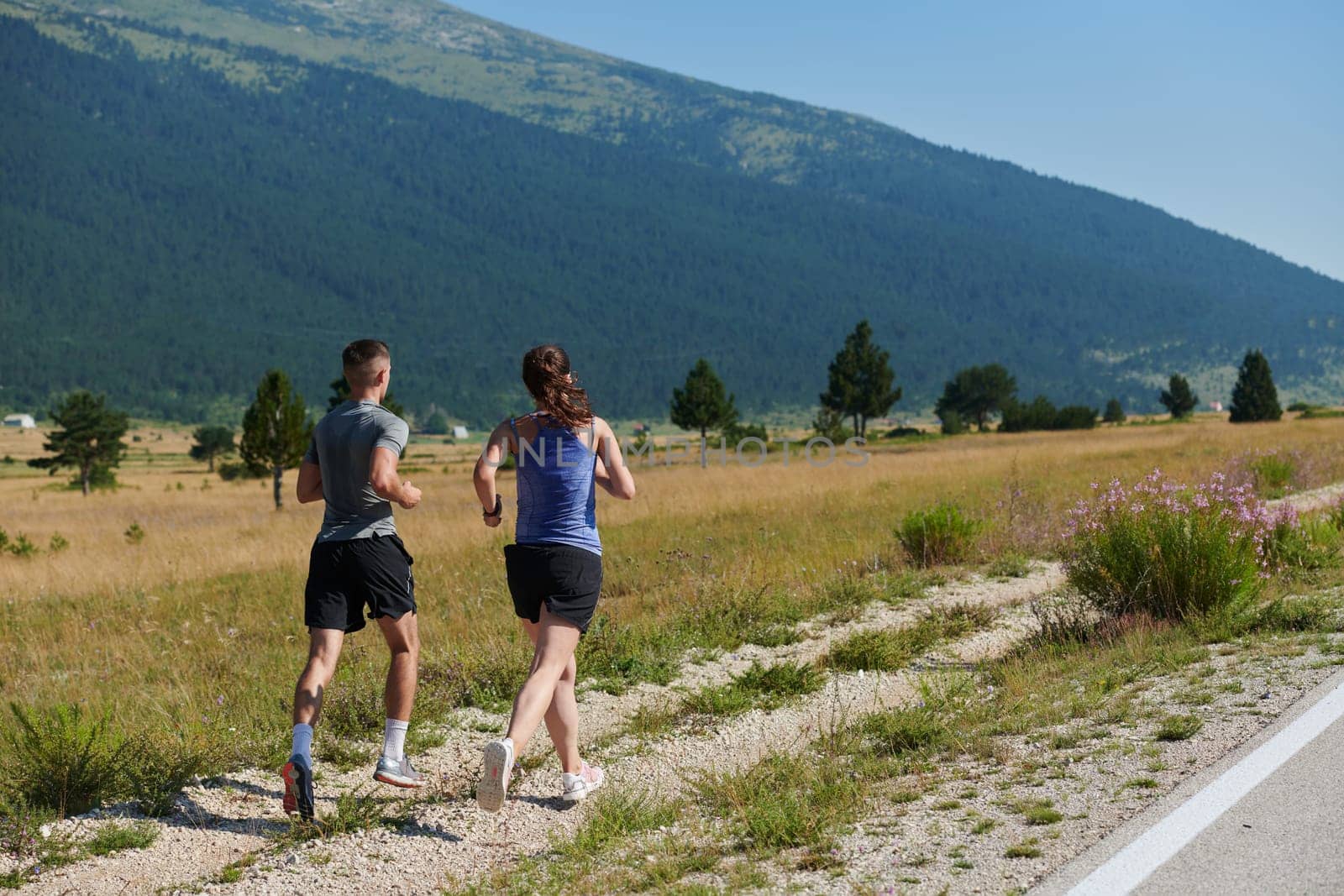 A vibrant couple dashes running the outdoors, embodying the essence of athleticism and romance, their confident strides reflecting a shared commitment to fitness and preparation for future marathon challenges.