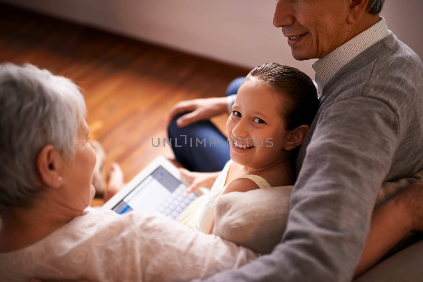 Child, grandparents and tablet on couch in home or online game or communication, teaching or connection. Elderly couple, retirement and girl or internet learning in apartment, development or bonding.