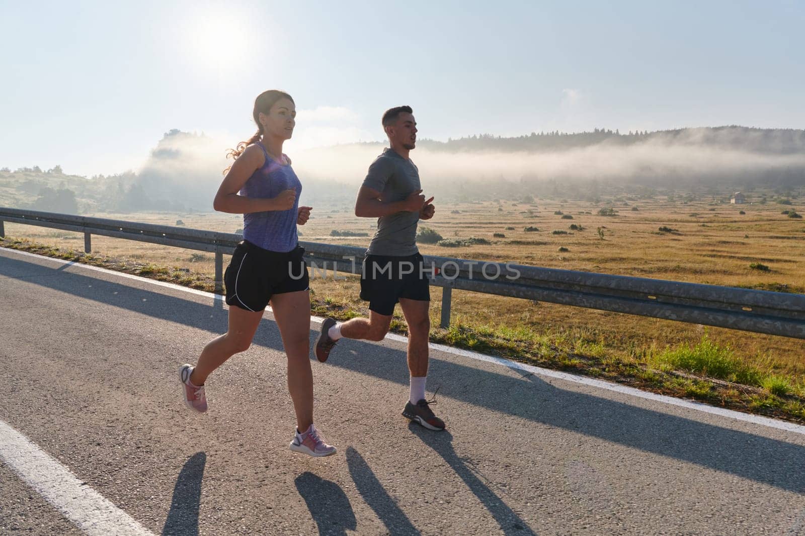 A couple runs through a sun-dappled road, their bodies strong and healthy, their love for each other and the outdoors evident in every stride.