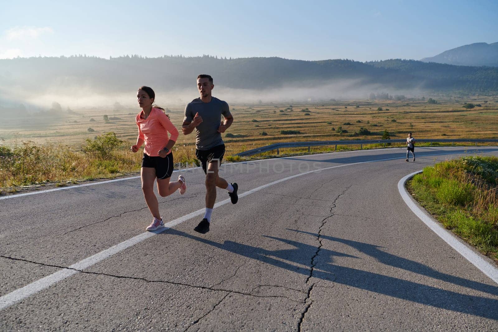 A couple runs through a sun-dappled road, their bodies strong and healthy, their love for each other and the outdoors evident in every stride.